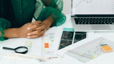 A person analyzes financial charts and graphs at a desk, indicating business trading activity.