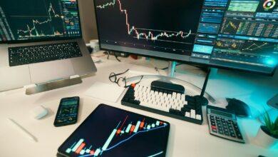 Stock charts are displayed on multiple screens.